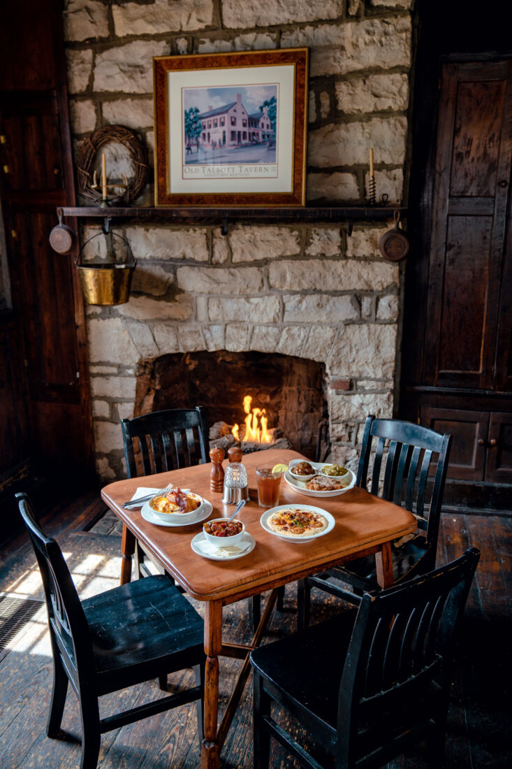 A table with four chairs with dishes next to a stone fireplace