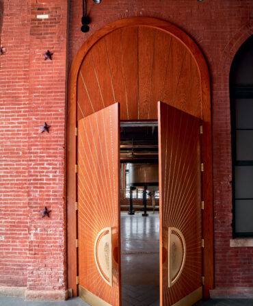 Large wooden doors with door handles halfway open to a distillery