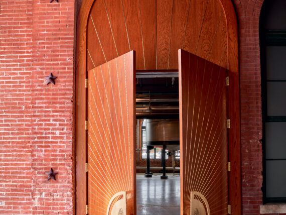 Large wooden doors with door handles halfway open to a distillery