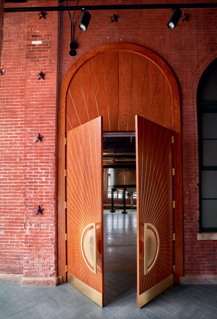 Large wooden doors with door handles halfway open to a distillery