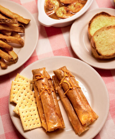 Plates of shrimp and tamales on a red and white checkered tablecloth