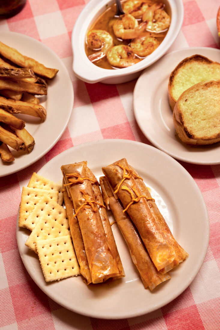 Plates of shrimp and tamales on a red and white checkered tablecloth