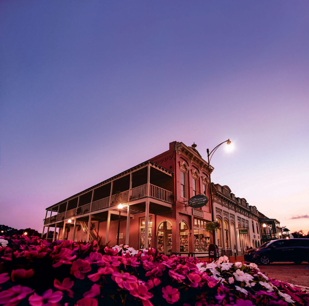 A bookstore at dusk with pink flowers in front of it