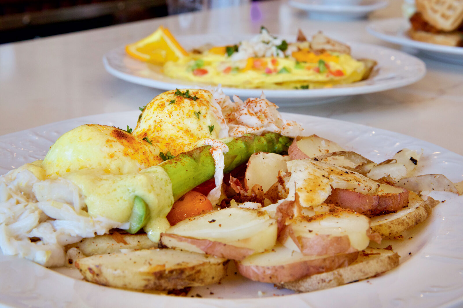 A plate of breakfast potatoes and poached eggs with hollandaise