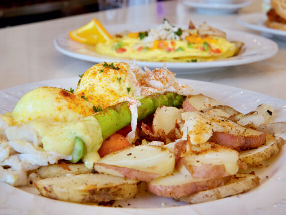 A plate of breakfast potatoes and poached eggs with hollandaise