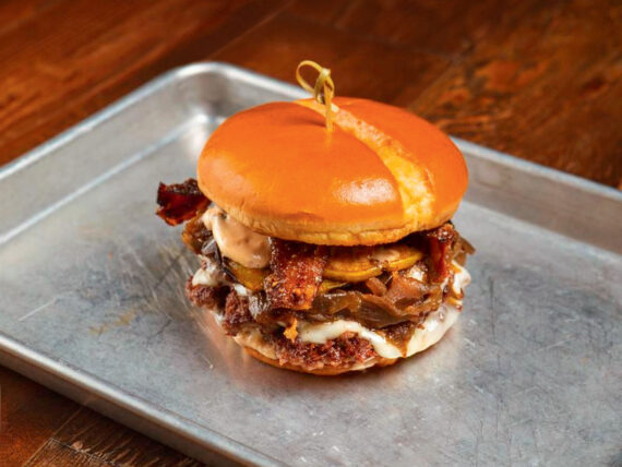 A burger with bacon and sauce on a silver tray