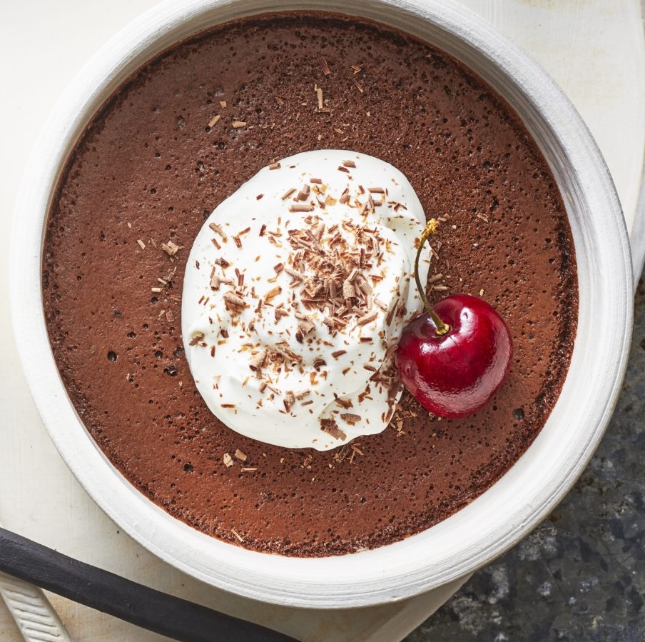 bitters-and-bourbon chocolate pot de crème with whipped cream, chocolate shavings, and a fresh cherry