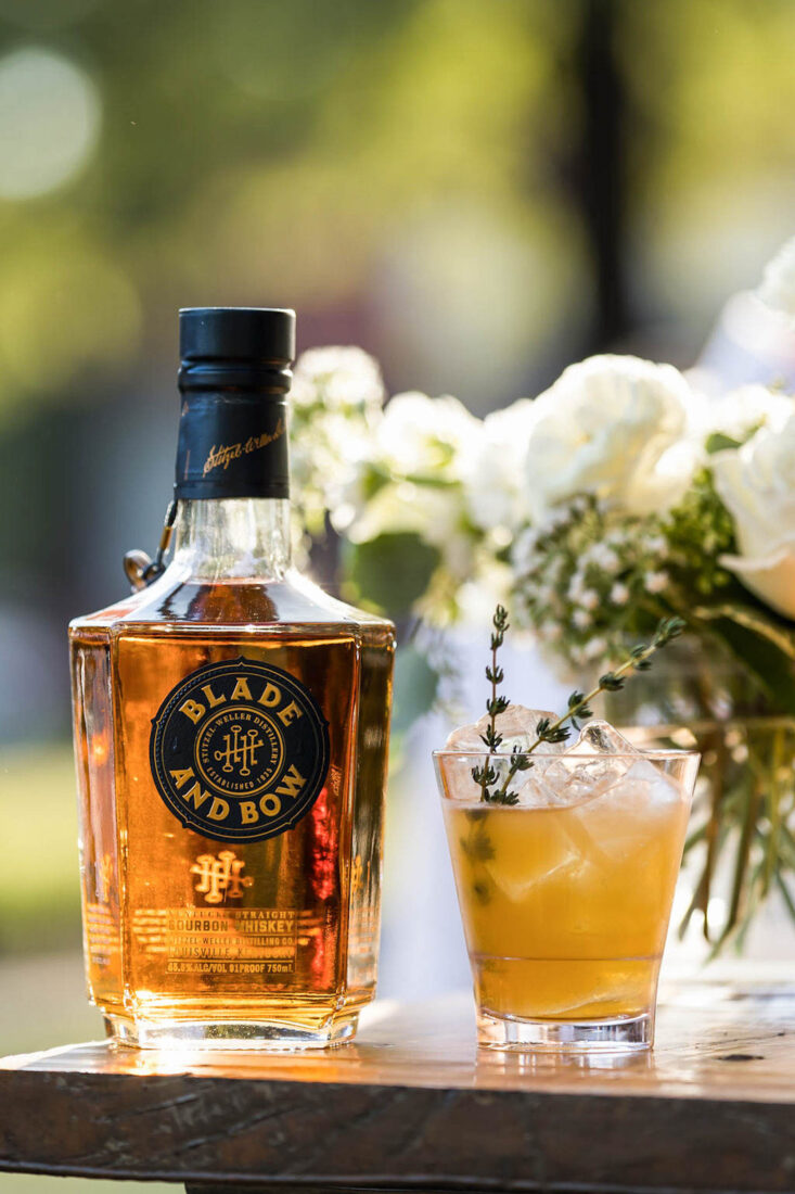 A bottle of bourbon by a cocktail