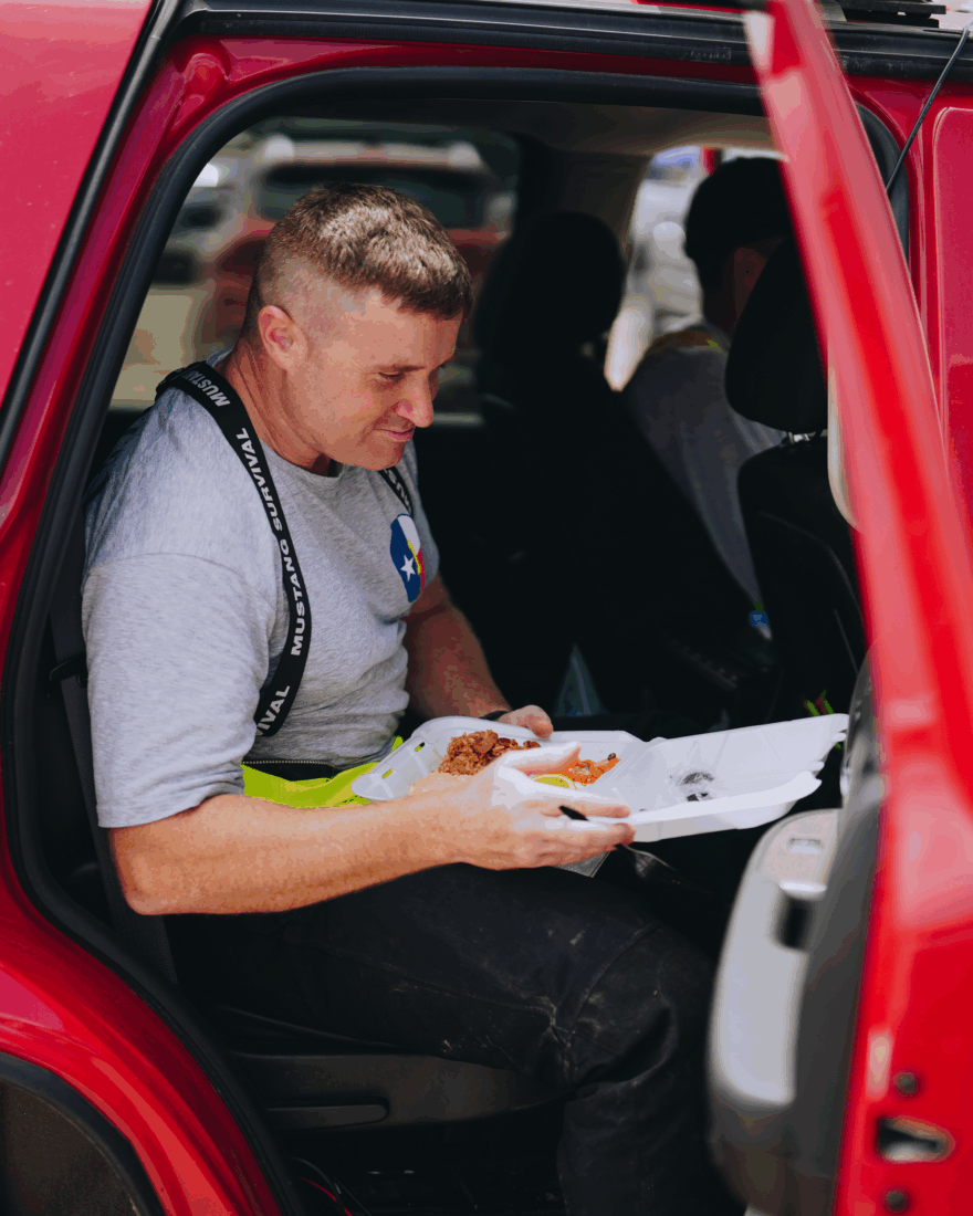 A first responder eats a boxed meal in a car