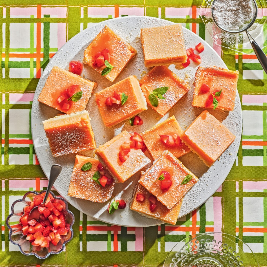 a plate of strawberry lemon bars with powdered sugar on a green and plaid backdrop