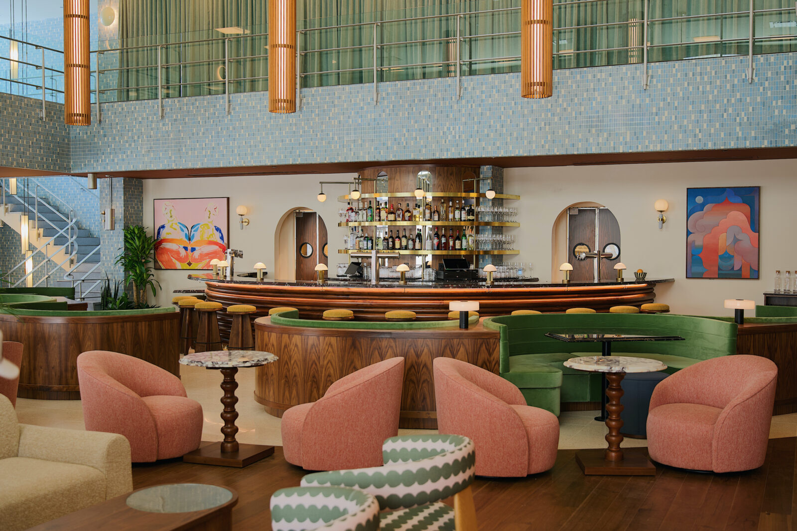 A big lobby bar with green walls and pink chairs