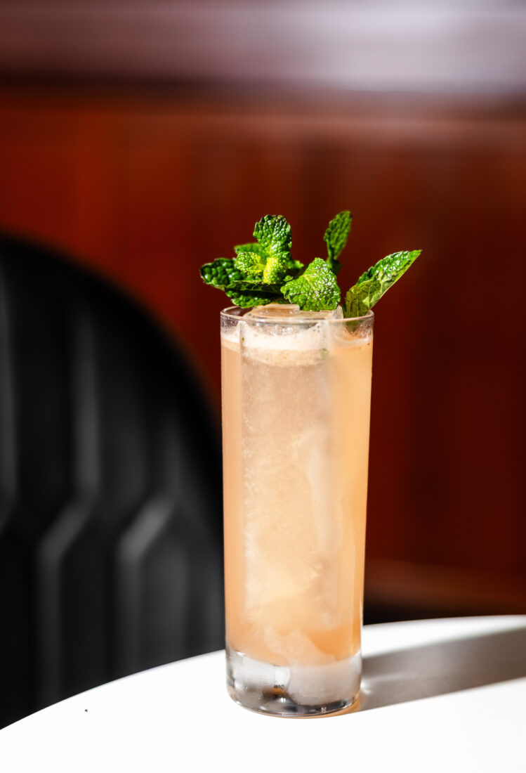 A light orange cocktail in a highball glass