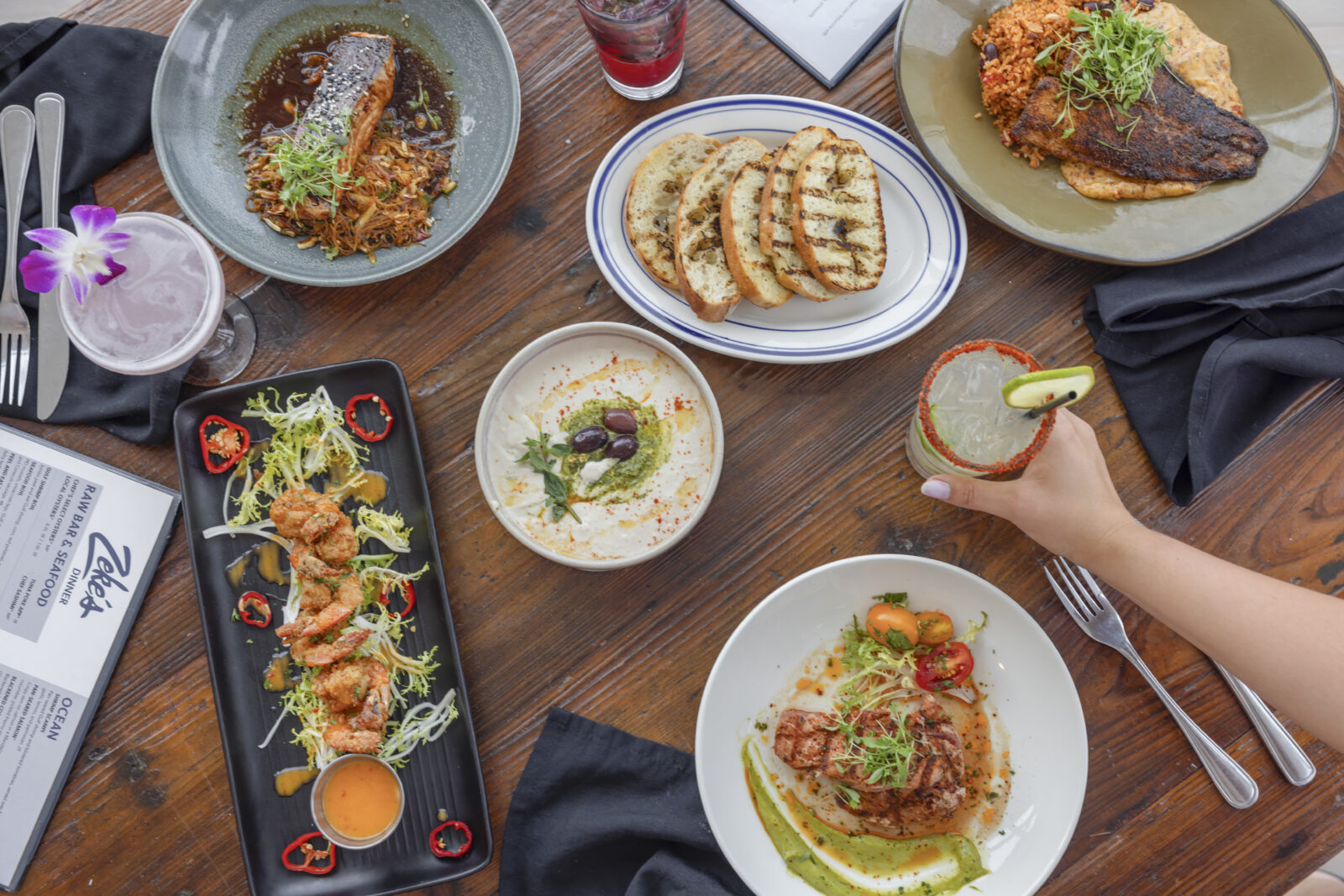 a table filled with different plates of seafood, tacos, and pasta