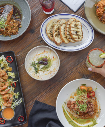 a table filled with different plates of seafood, tacos, and pasta