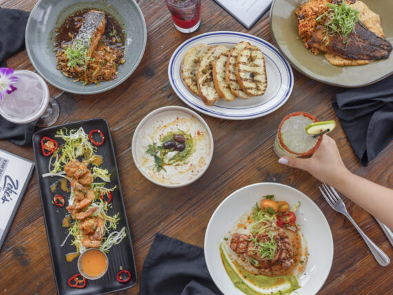 a table filled with different plates of seafood, tacos, and pasta
