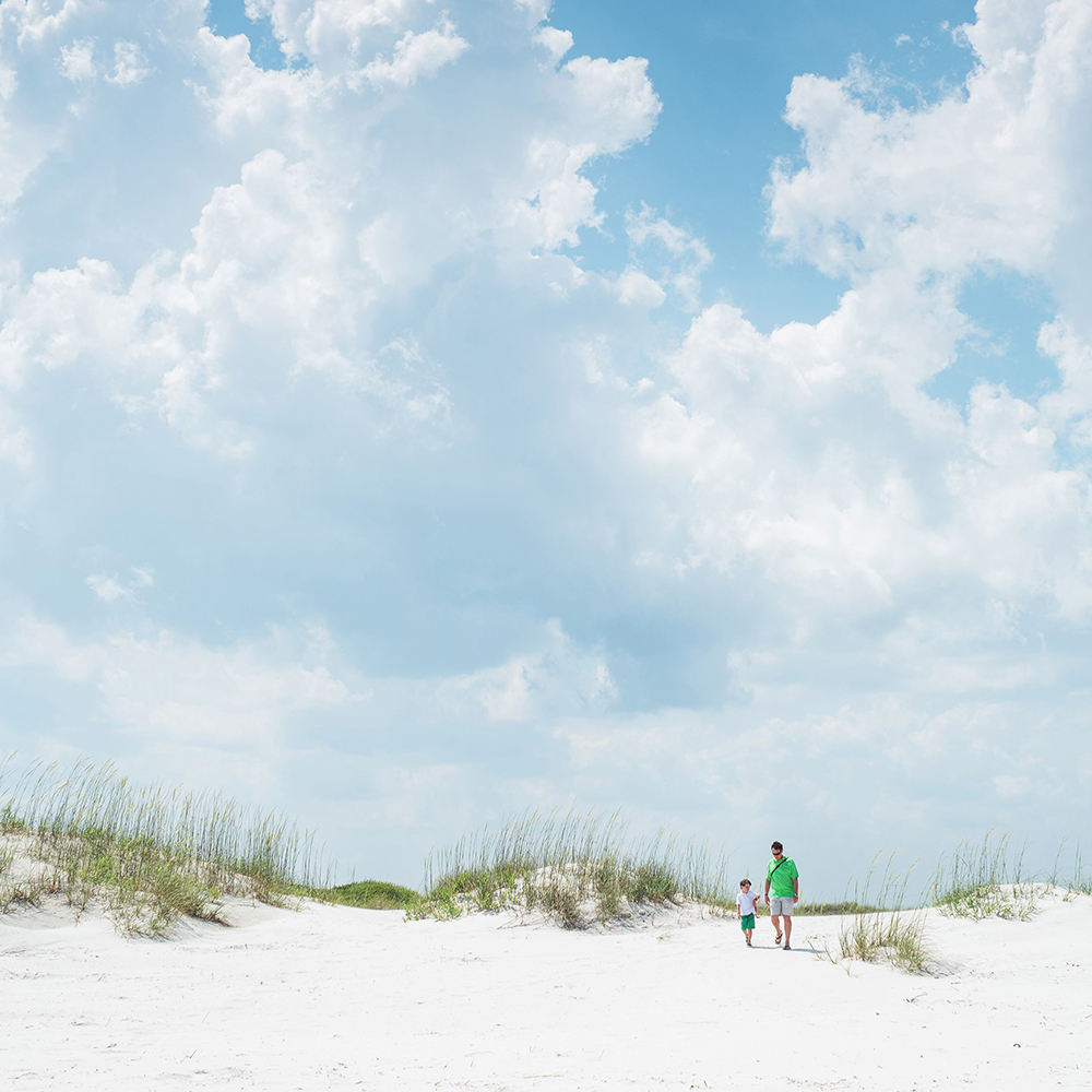a boy and father walk on the beach