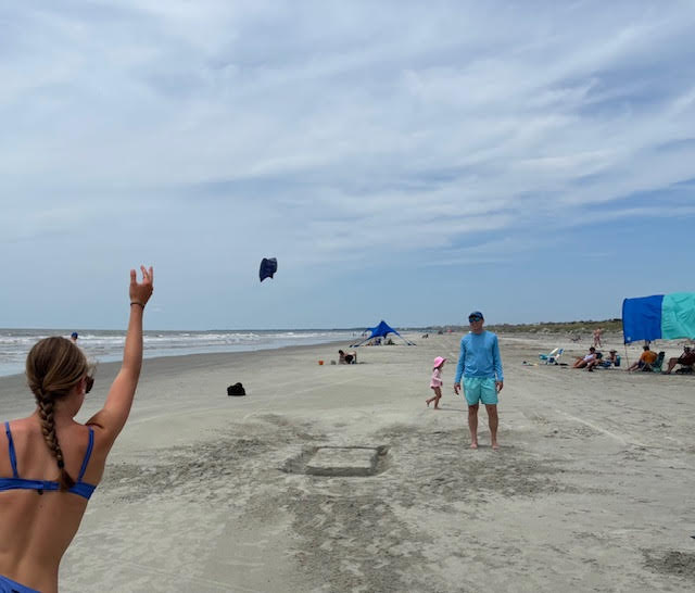 People play corn hole on the beach