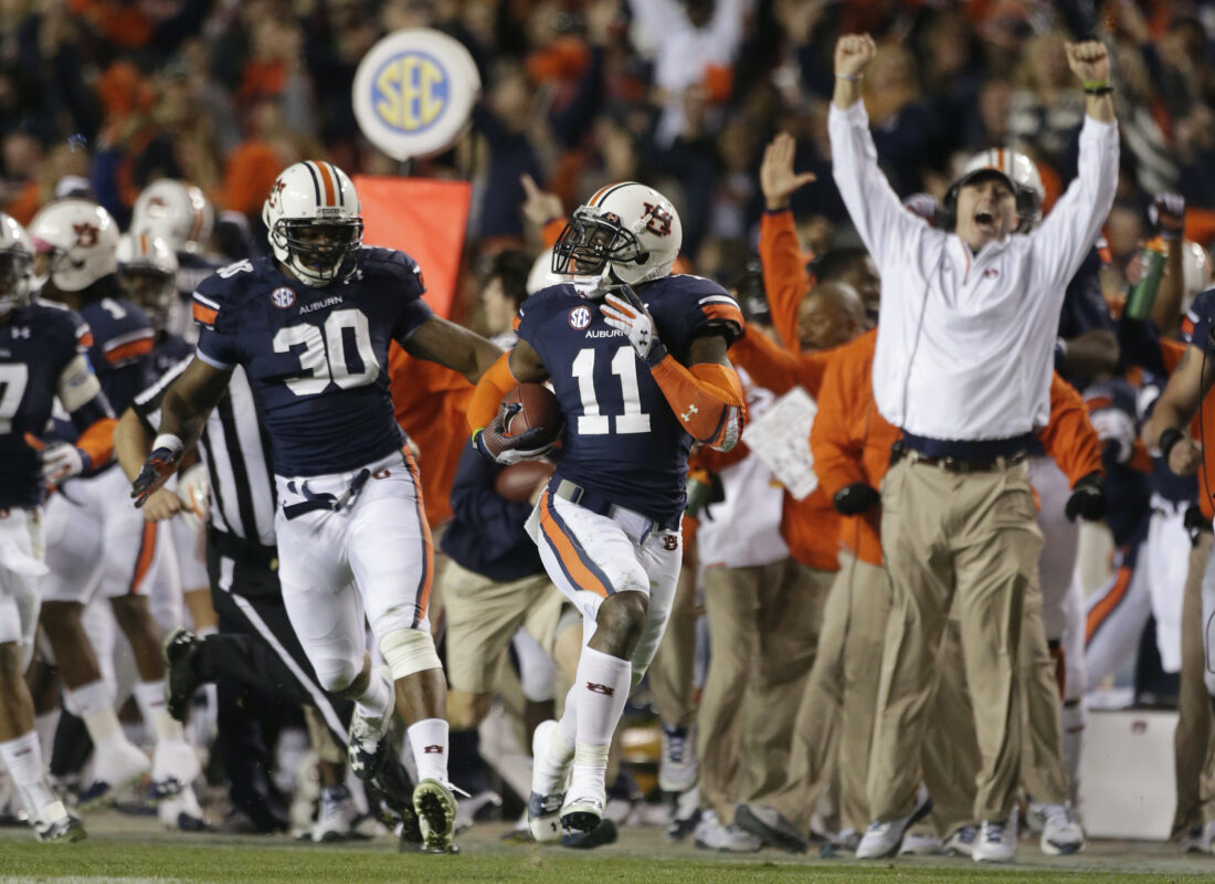 A coach and football players cheer on a field