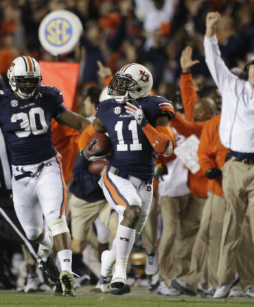 A coach and football players cheer on a field