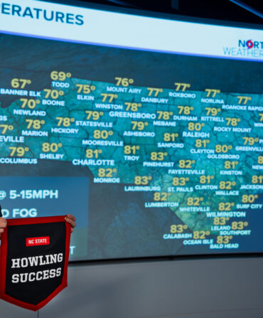 A man poses with a banner in front of a weather screen