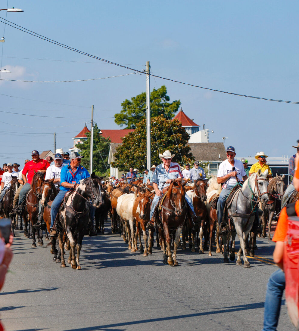 People ride horses in a crowd through the street