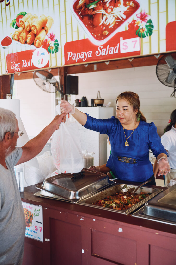 A woman behind a counter hands a bag of food to a customer