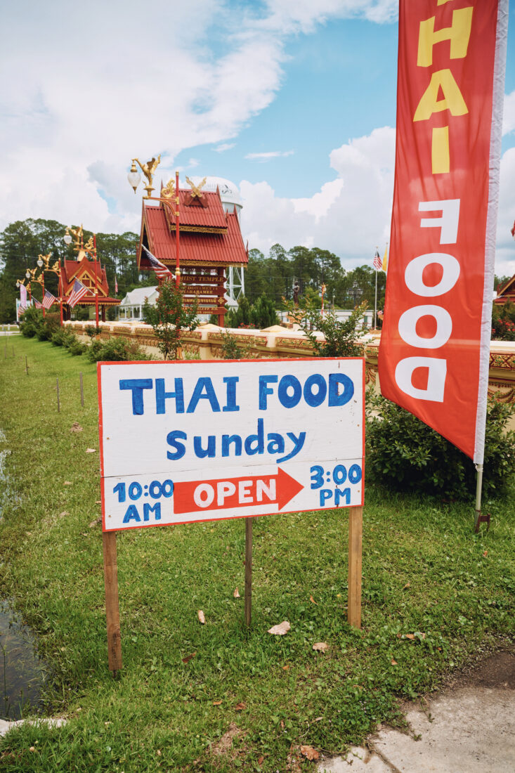 A sign on the side of the road directs people to thai food