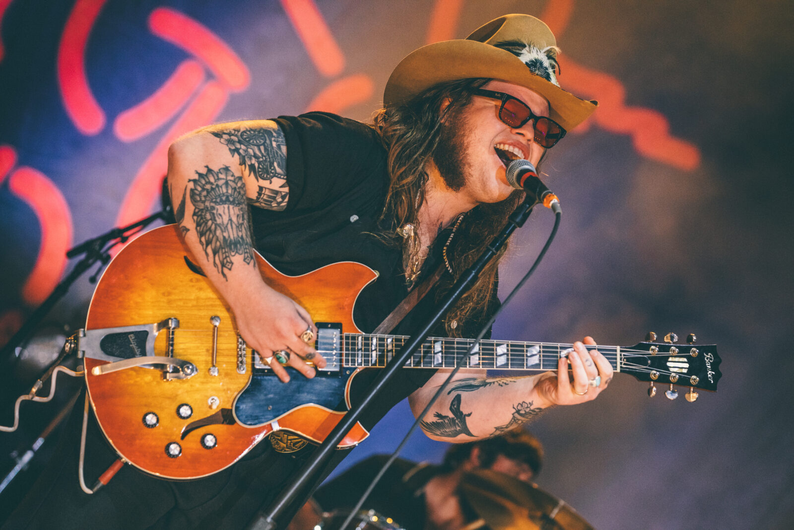 A portrait of a man singing on a stage holding a guitar
