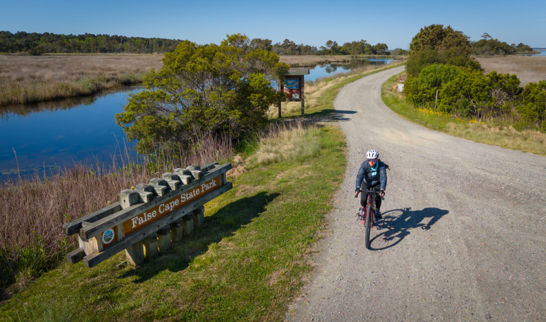 A man bikes on a path outdoors by the water