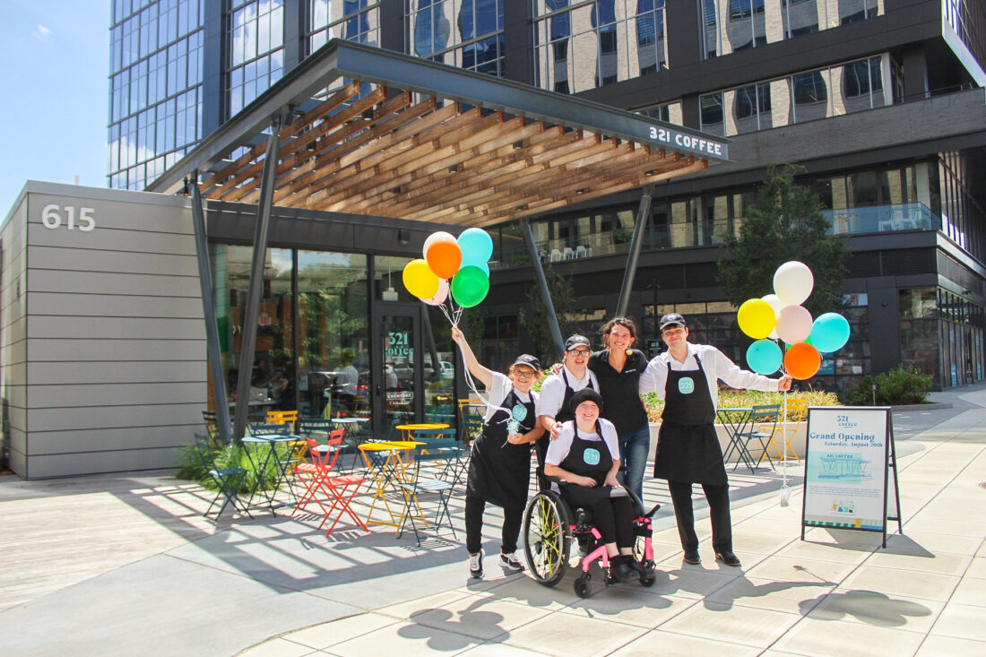 a group of people outside a coffee shop with balloons