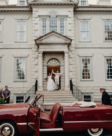 a bride and groom exit a church in front of a custom Ford convertible