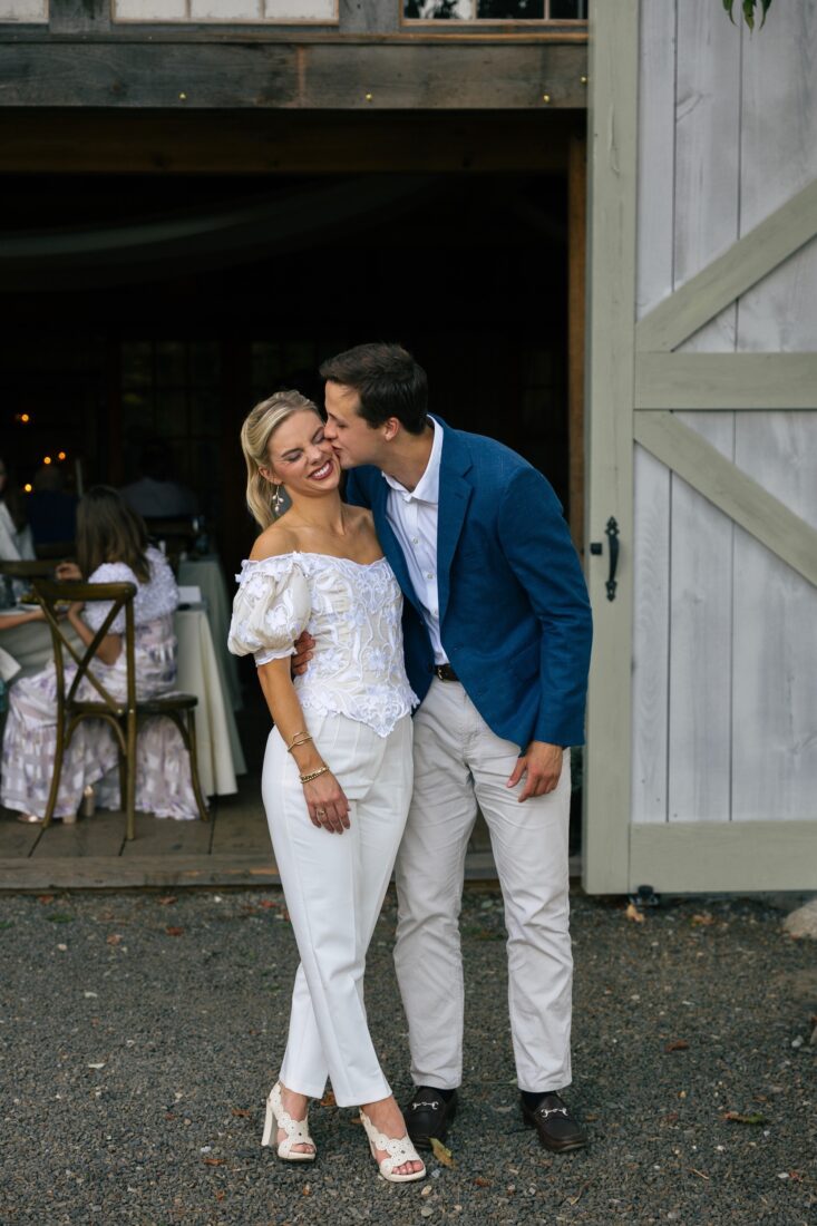 A couple kisses outside barn doors
