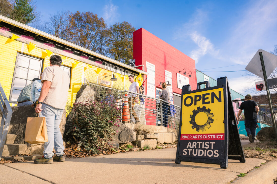 An open artist studio sign on a sidewalk