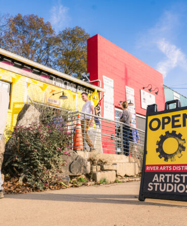 An open artist studio sign on a sidewalk