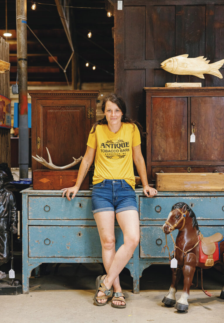 A woman in a yellow shirt stands in front of a blue dresser