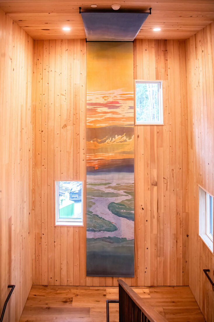 A creek landscape on a long piece of artwork in a stairwell