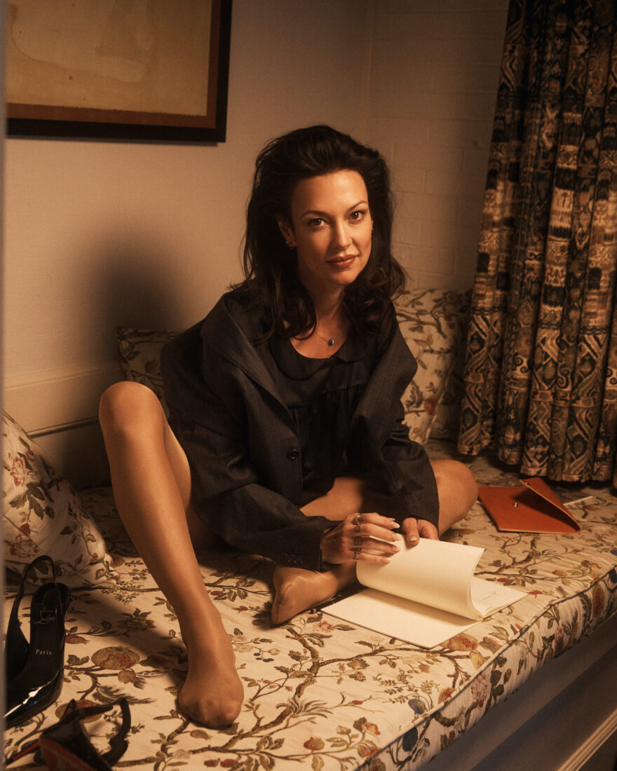 A portrait of a woman writing on paper on a bed