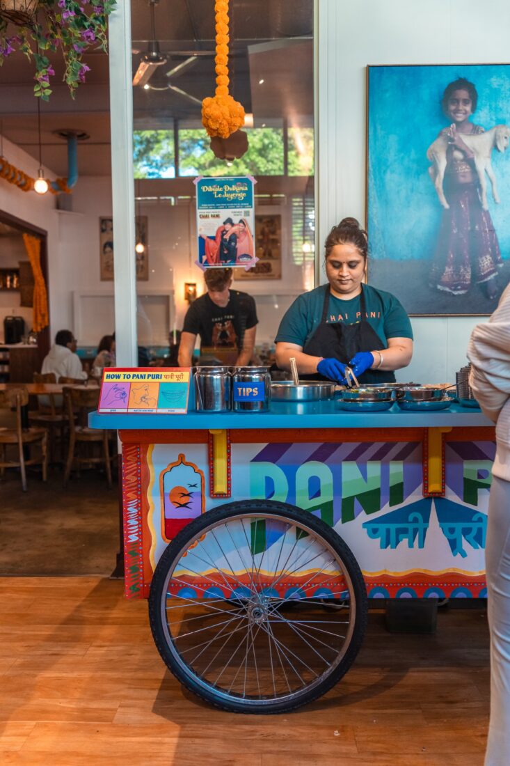 a woman stands behind a colorful cart
