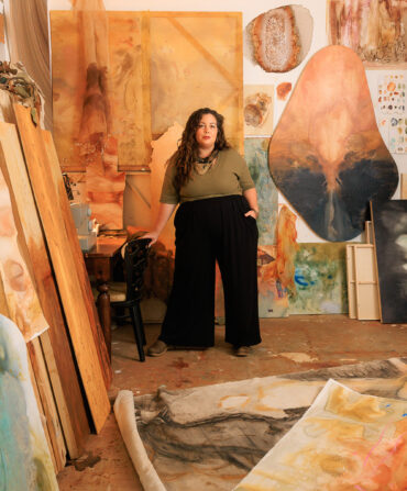 A woman in an art studio surrounded by earthy paintings