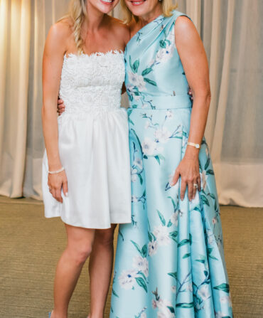 A bride stands next to her mother who wears a light blue dress