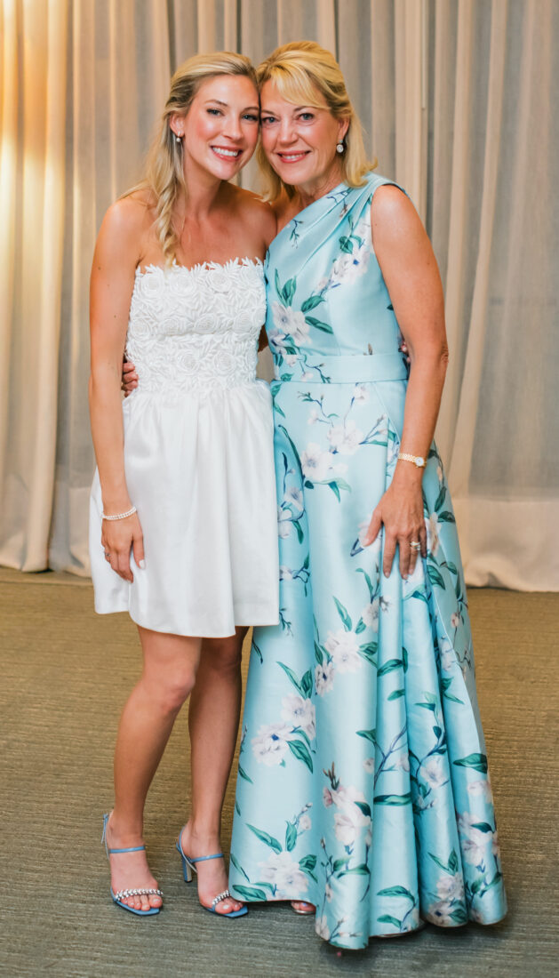A bride stands next to her mother who wears a light blue dress