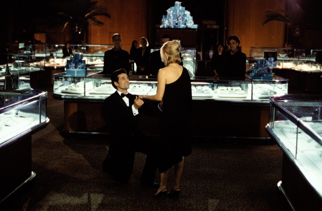A movie still from Sweet Home Alabama of a man kneeling in a jewelry store to propose to a blonde woman