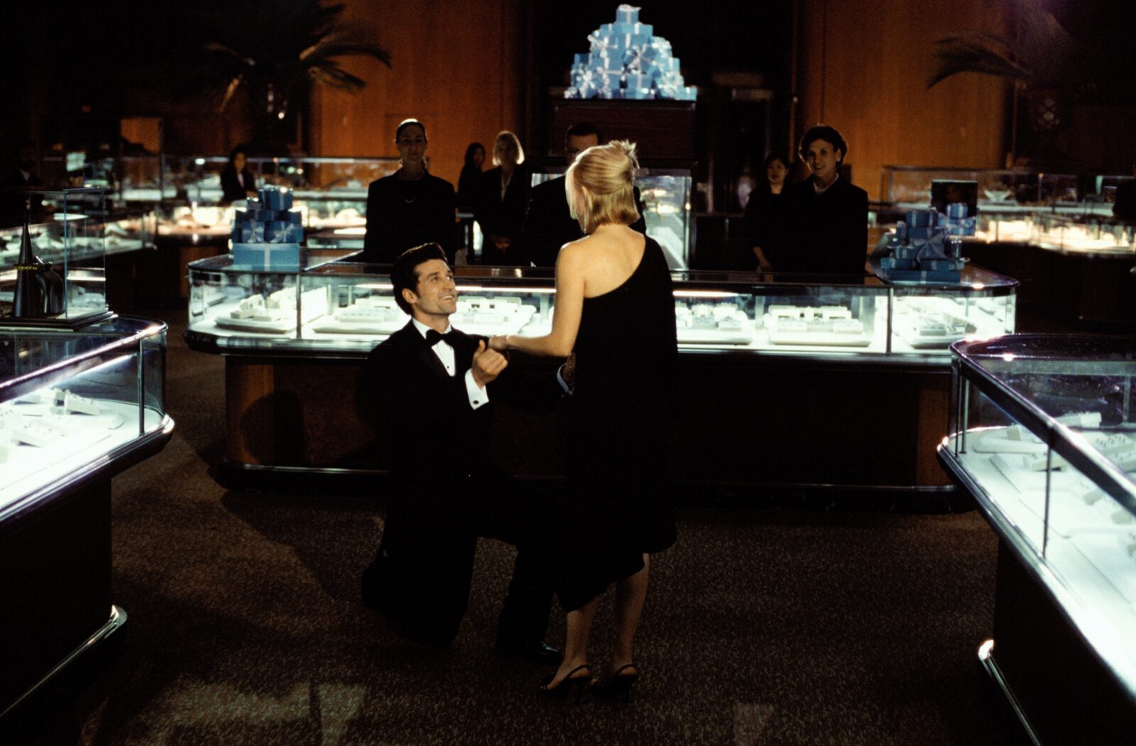 A movie still from Sweet Home Alabama of a man kneeling in a jewelry store to propose to a blonde woman