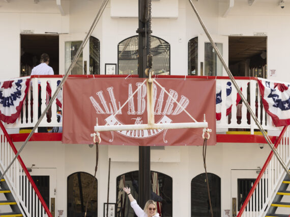 A woman stands on a boat decorated with fourth of july banners