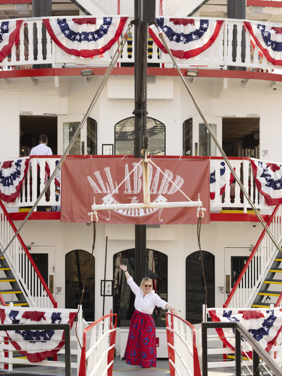 A woman stands on a boat decorated with fourth of july banners