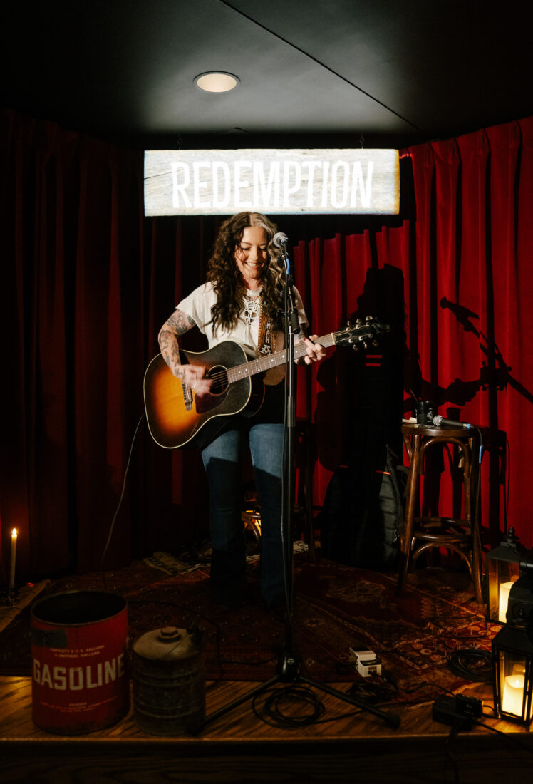 A woman plays a guitar on a stage