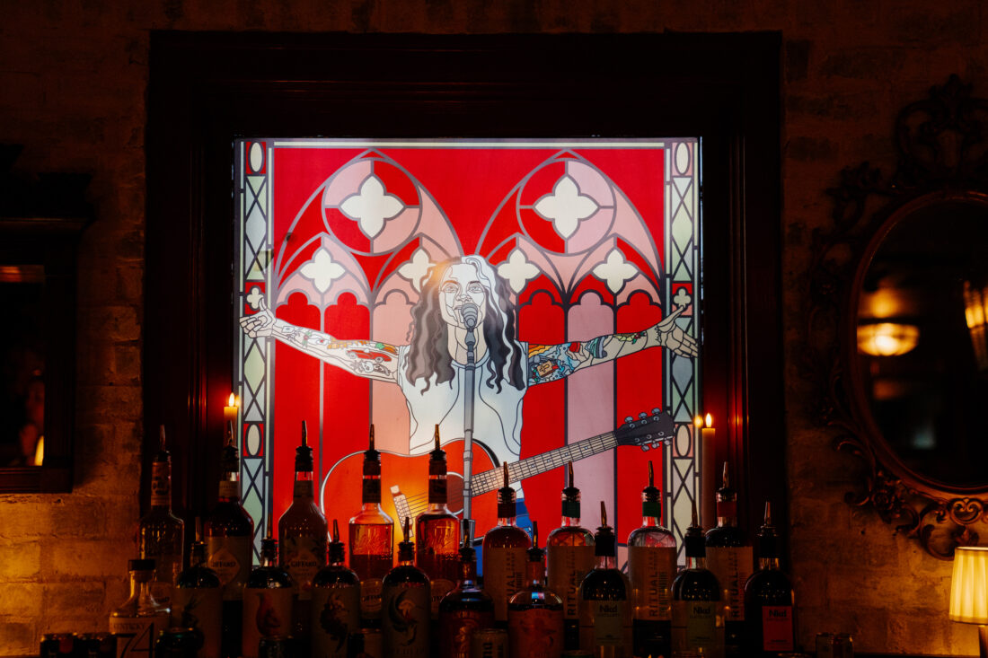 A stained glass portrait of a woman behind a bar