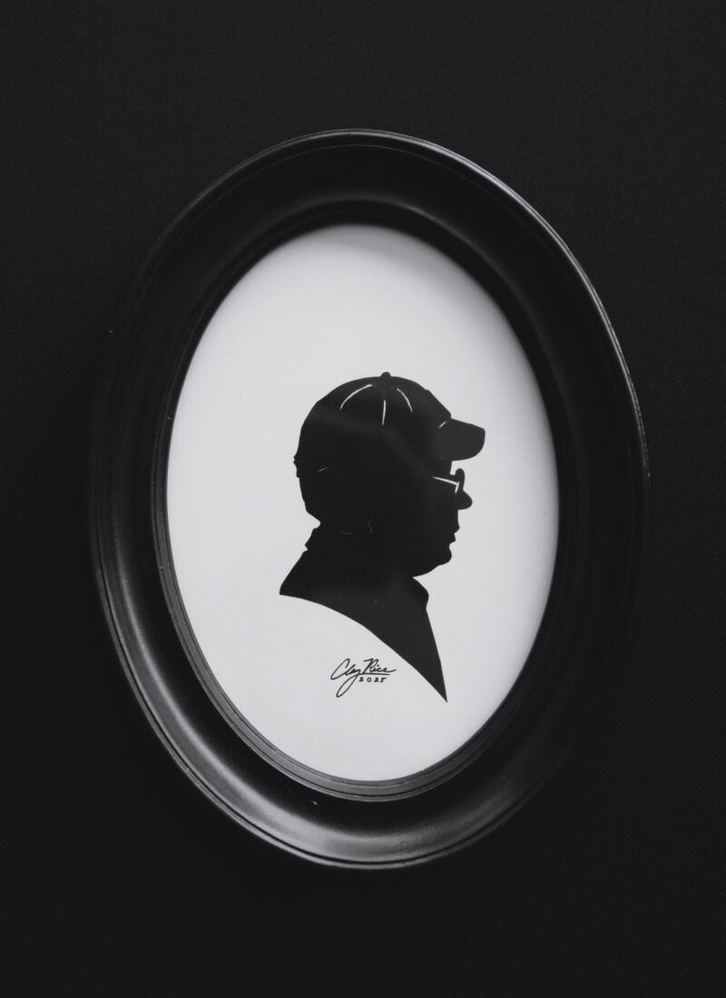 A silhouette portrait of a man with a hat and glasses