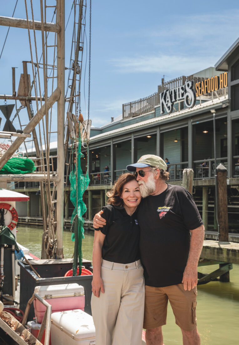 A portrait of a couple outside a seafood house by the water