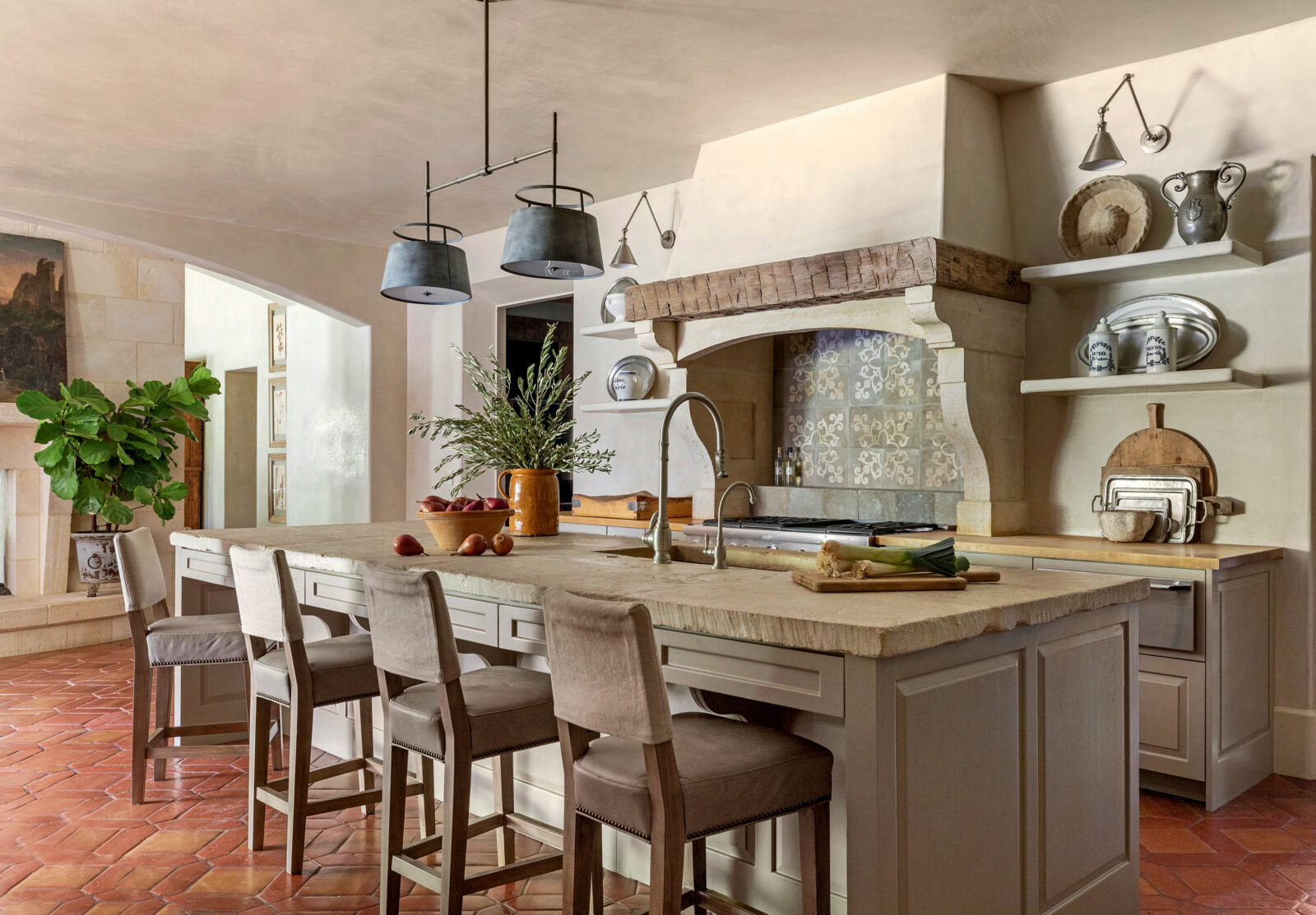A stone island centers a kitchen with clay-colored floors